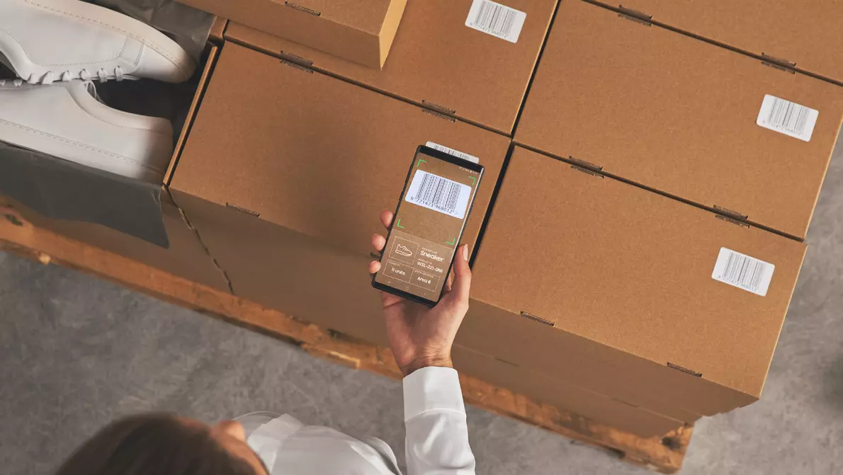 Samsung Geräte im Einzelhandelumfeld Mitarbeiterin scannt Schuhboxen mit dem Smartphone