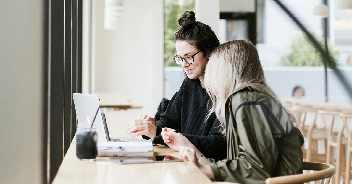 KOMSA Academy Unify Trainings Zwei Kolleginnen sitzen am Laptop während Coaching