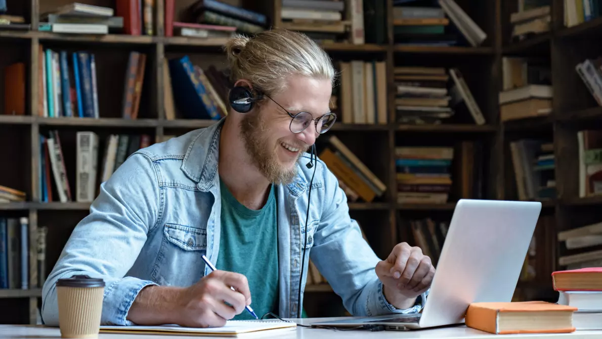 KOMSA Academy Teaser Mann sitzt im Homeoffice und nimmt am Laptop an Schulung teil