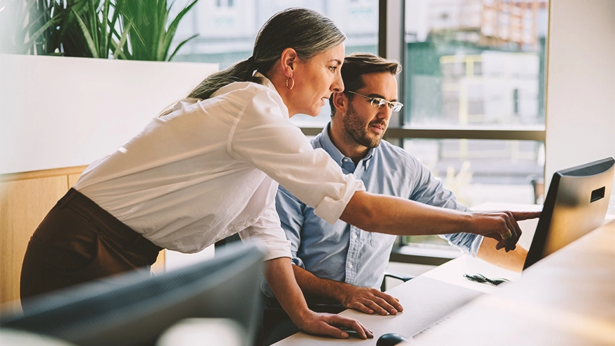 two people in front of a desktop pc discussing something two people in front of a desktop pc discussing something